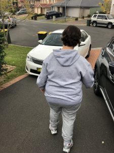 Image of a female person ready for the outdoor activity walking down the driveway