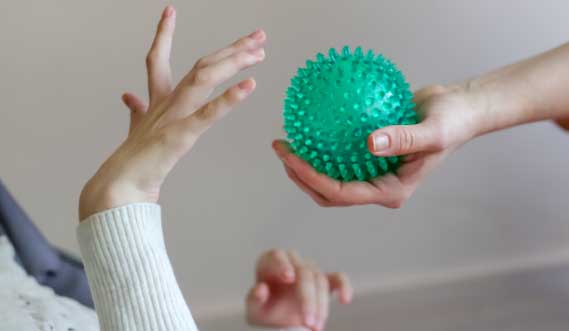 A child reaches to touch a green massage ball