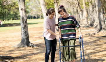 Image of Physiotherapist with the female exercise walking with the walking frame in the park