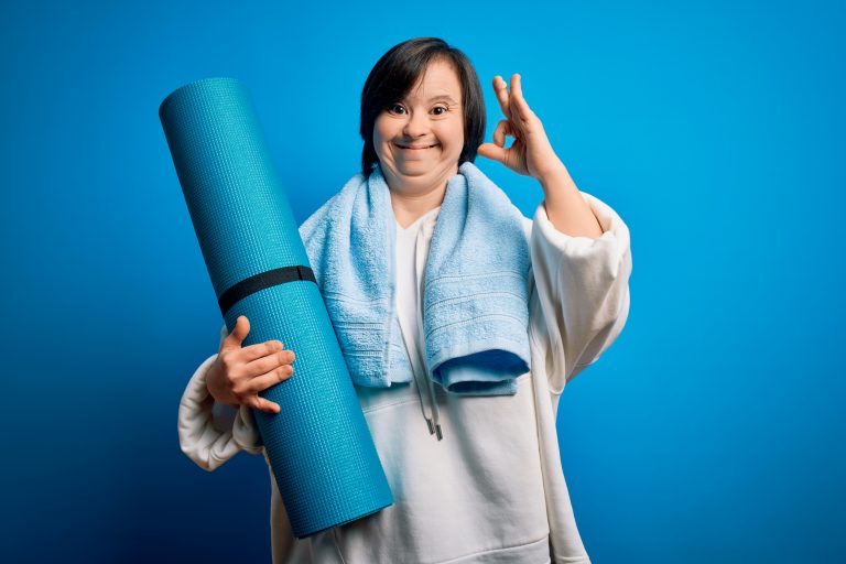 Picture of a young woman with Down syndrome dressed in exercise gear and holding an exercise mat