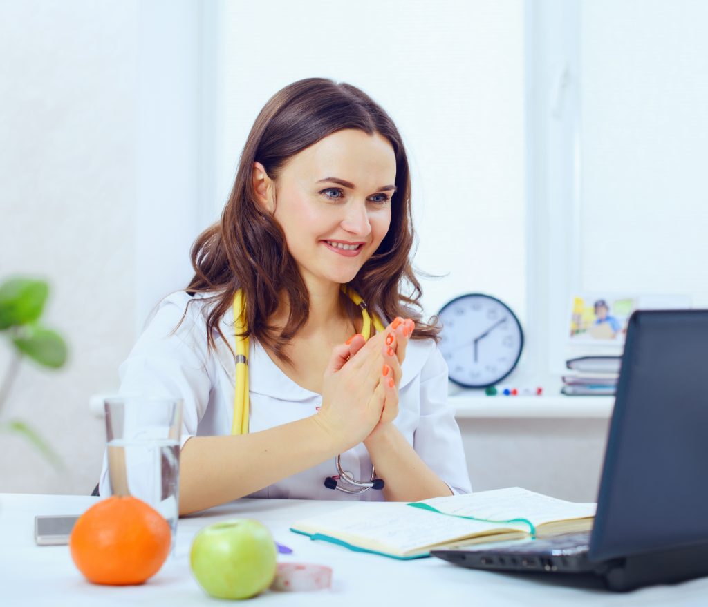 Young female nutritionist or dietitian sitting at her desk with computer open